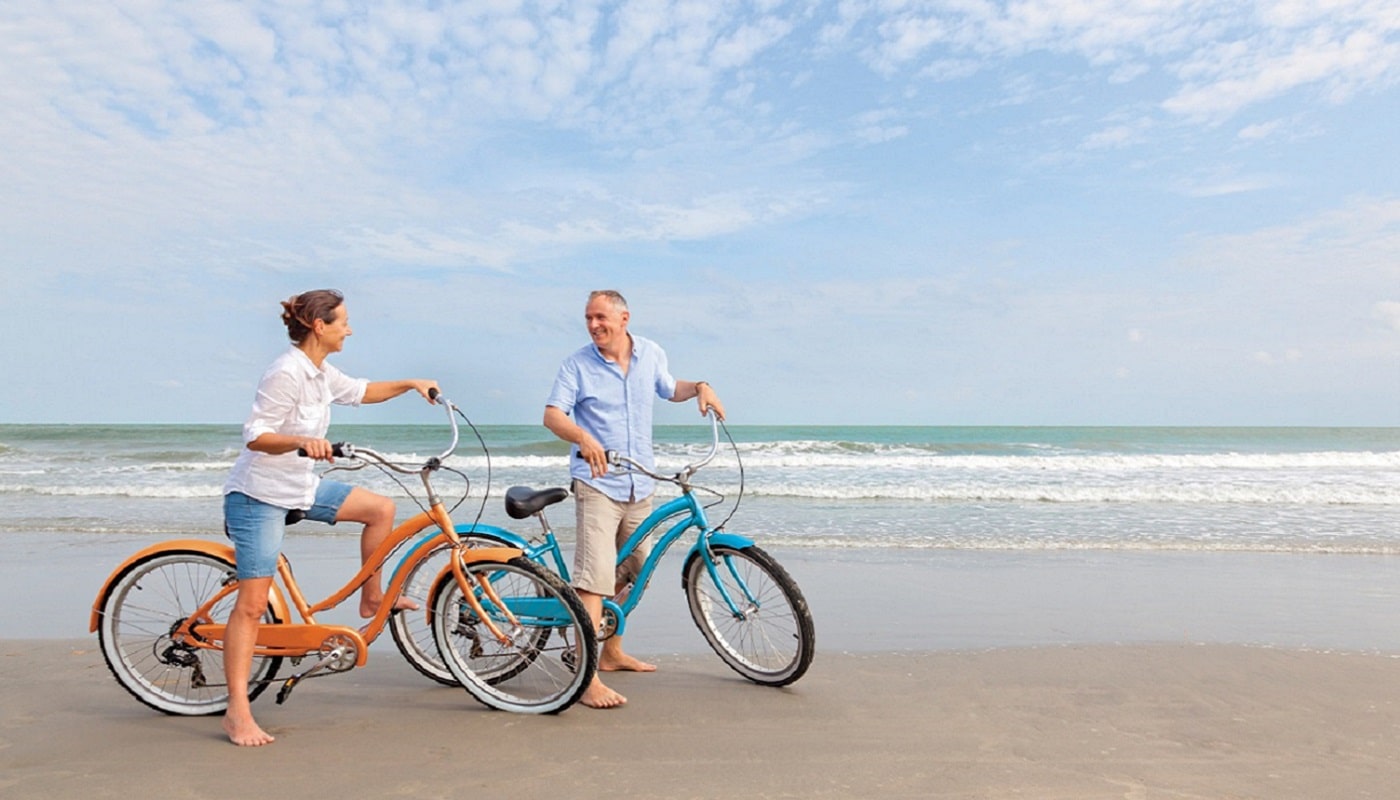 Retired seniors enjoying a bike ride on a beach