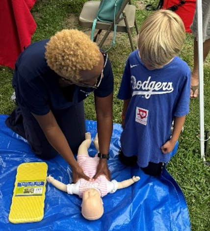 MemorialCare nurses demonstrate Hands-Only CPR on a pediatric mannikin to elders and kids at the CPR Sidewalk Event.