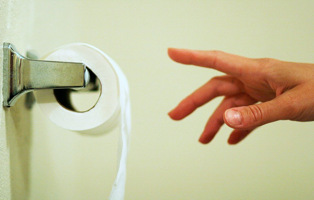 Image of a hand reaching for toilet paper