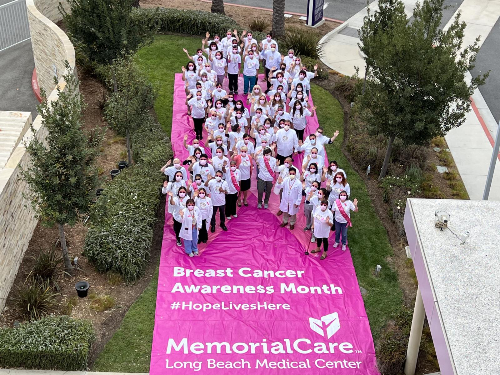 Physicians, employees, and cancer survivors create a giant human awareness ribbon to draw attention  to the importance of breast cancer screenings.